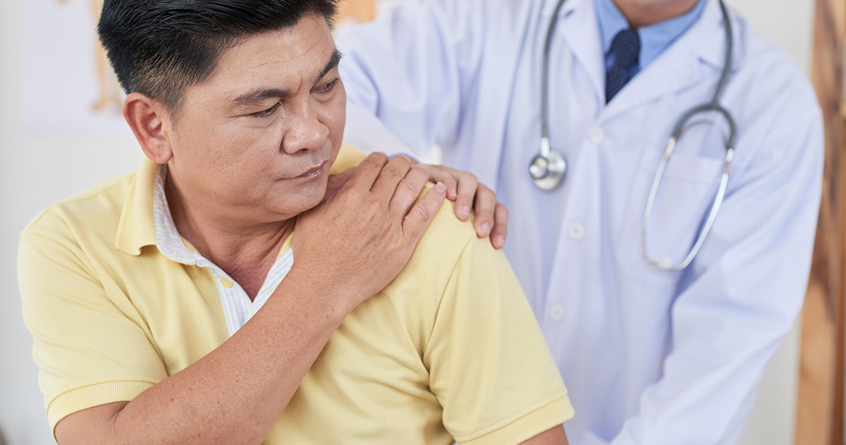 Senior man visiting doctor as he is suffering from shoulder pain